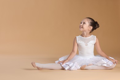 Portrait of little ballerina on beige background