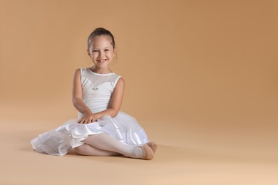 Photo of Portrait of little ballerina on beige background, space for text