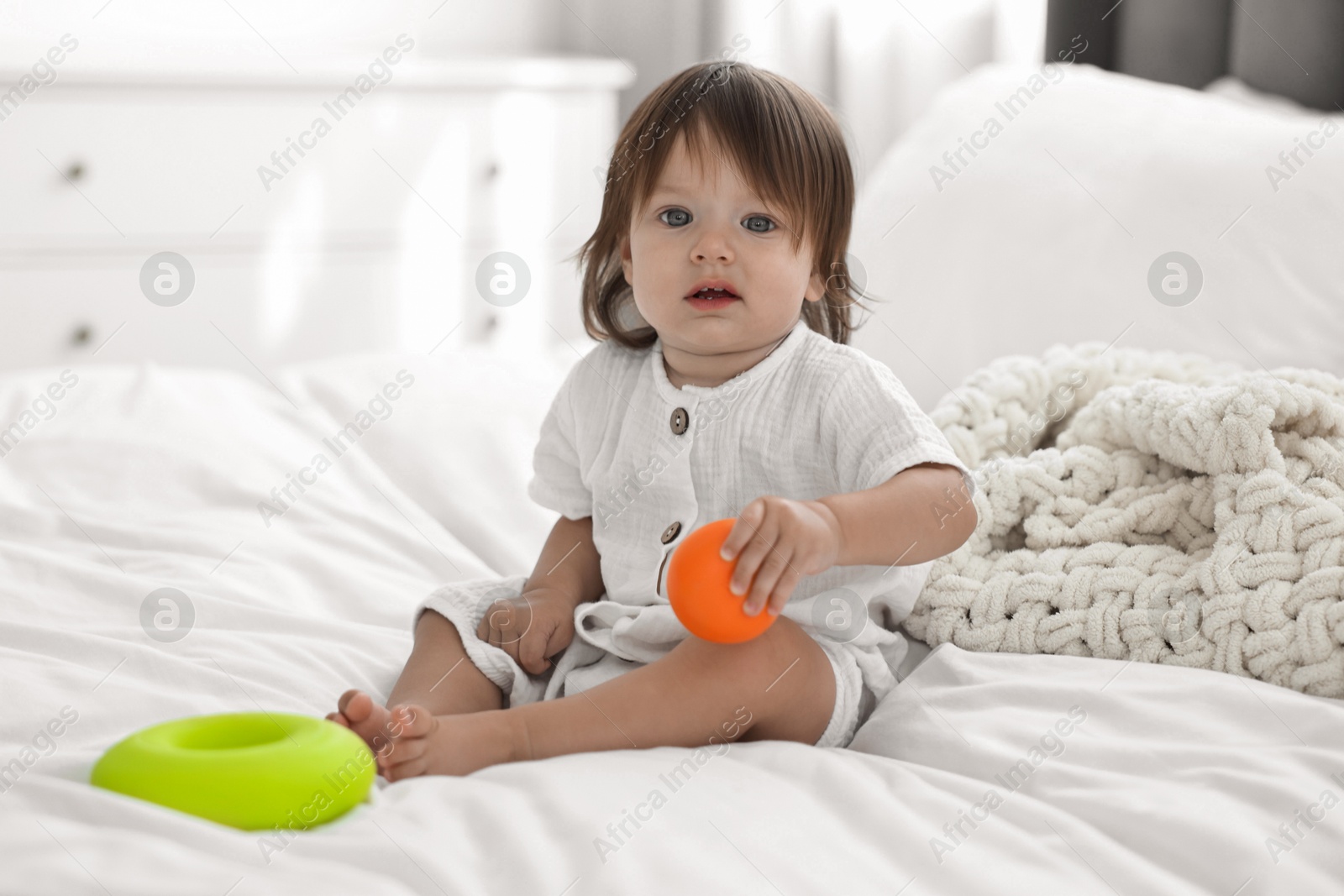 Photo of Cute little baby with toys on bed at home