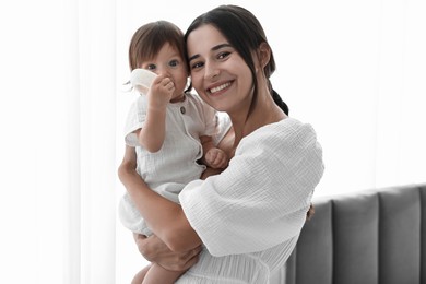 Photo of Beautiful young mother with her cute little baby indoors