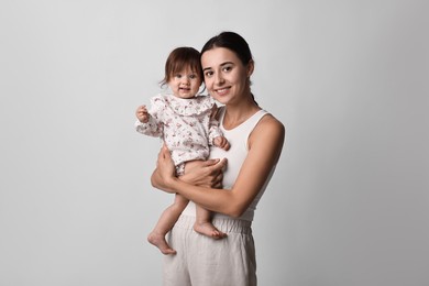 Photo of Beautiful young mother and her cute little baby on light grey background