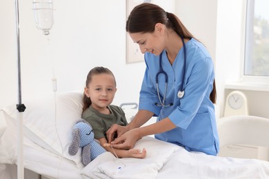 Photo of Doctor examining little girl on bed at hospital