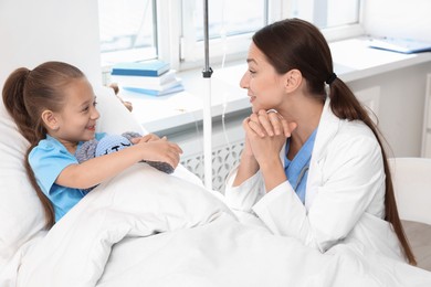 Doctor examining little girl on bed at hospital