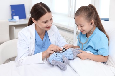 Doctor examining little girl on bed at hospital