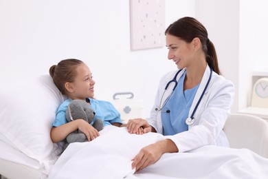 Photo of Doctor examining little girl on bed at hospital