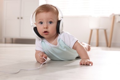 Cute little baby with headphones on floor at home