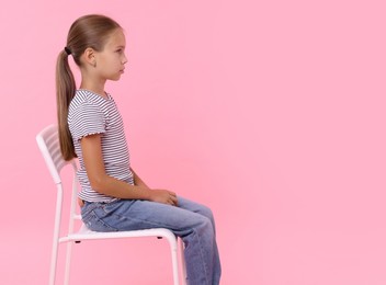 Girl with correct posture sitting on chair against pink background, space for text