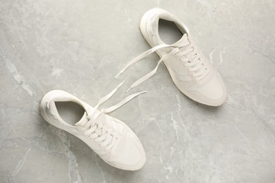 Photo of Pair of stylish sneakers on grey marble background, top view