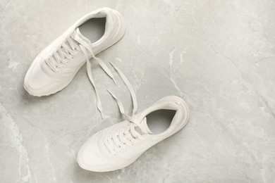 Photo of Pair of stylish sneakers on grey marble background, top view