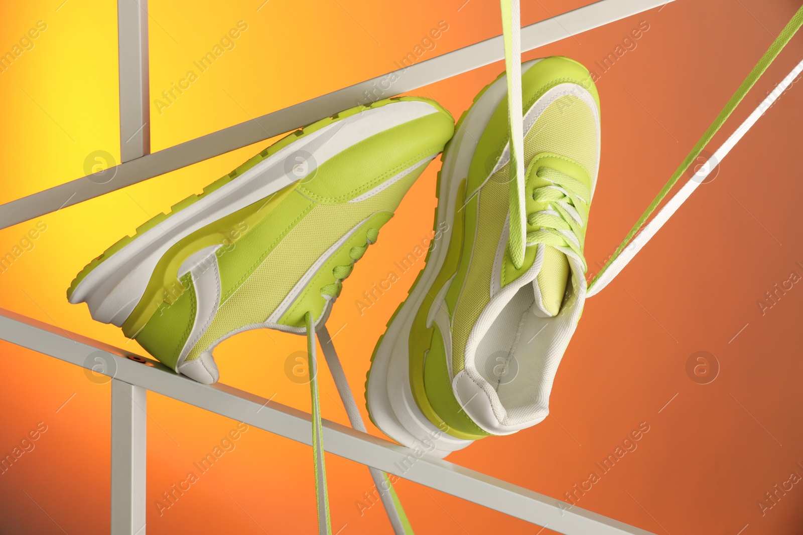 Photo of Stylish presentation of sneakers against color background