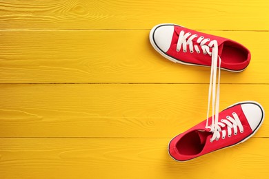 Pair of stylish sneakers on yellow wooden background, top view. Space for text