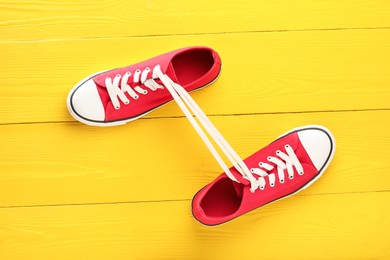 Photo of Pair of stylish sneakers on yellow wooden background, top view