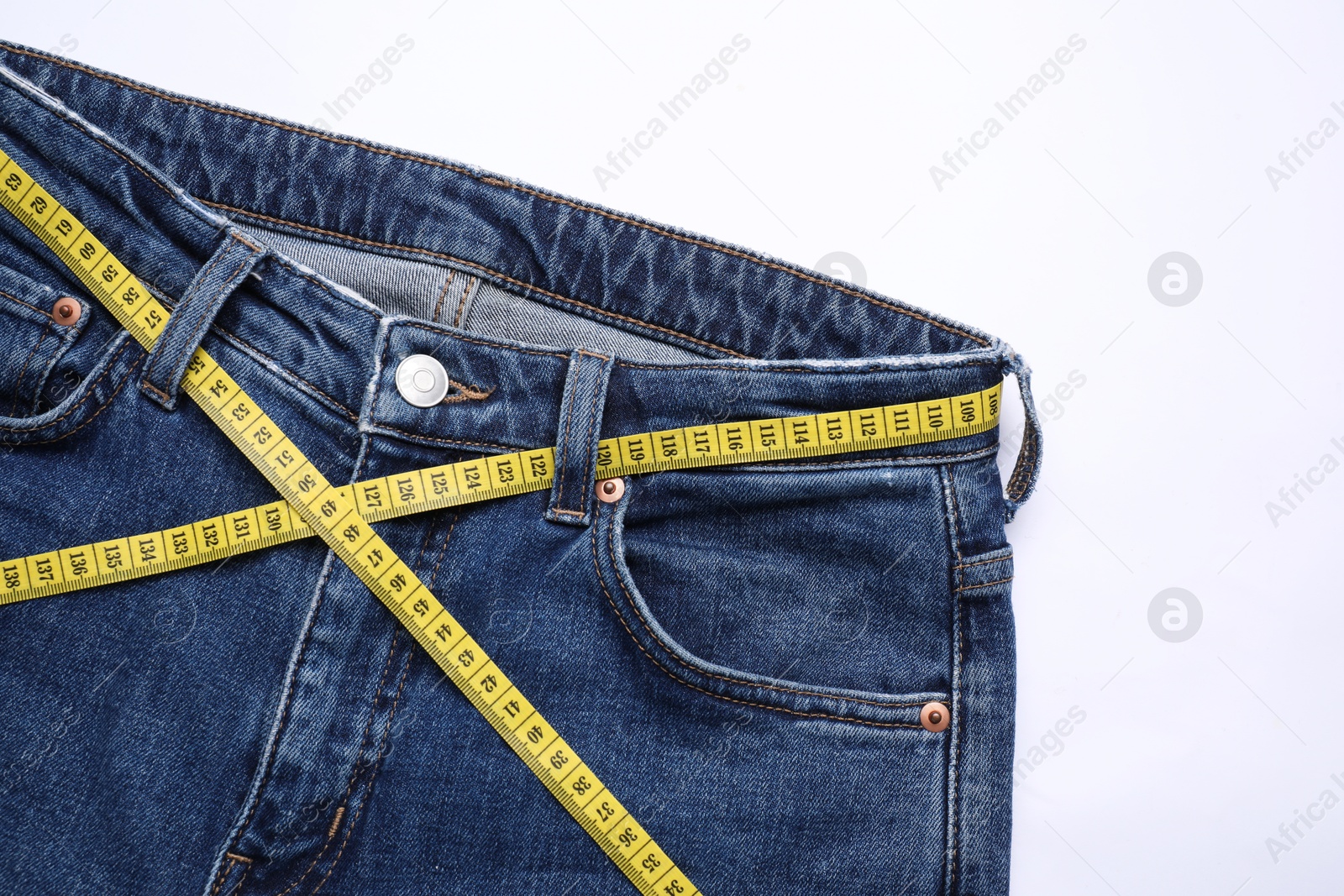 Photo of Jeans and measuring tape on white background, top view