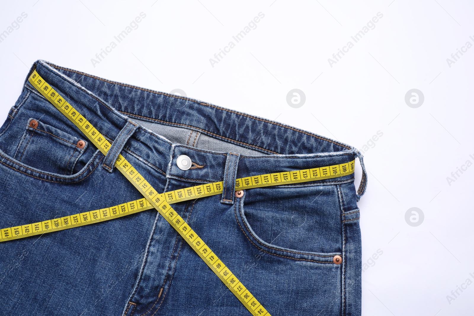 Photo of Jeans and measuring tape on white background, top view