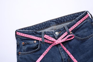 Photo of Jeans and measuring tape on white background, top view