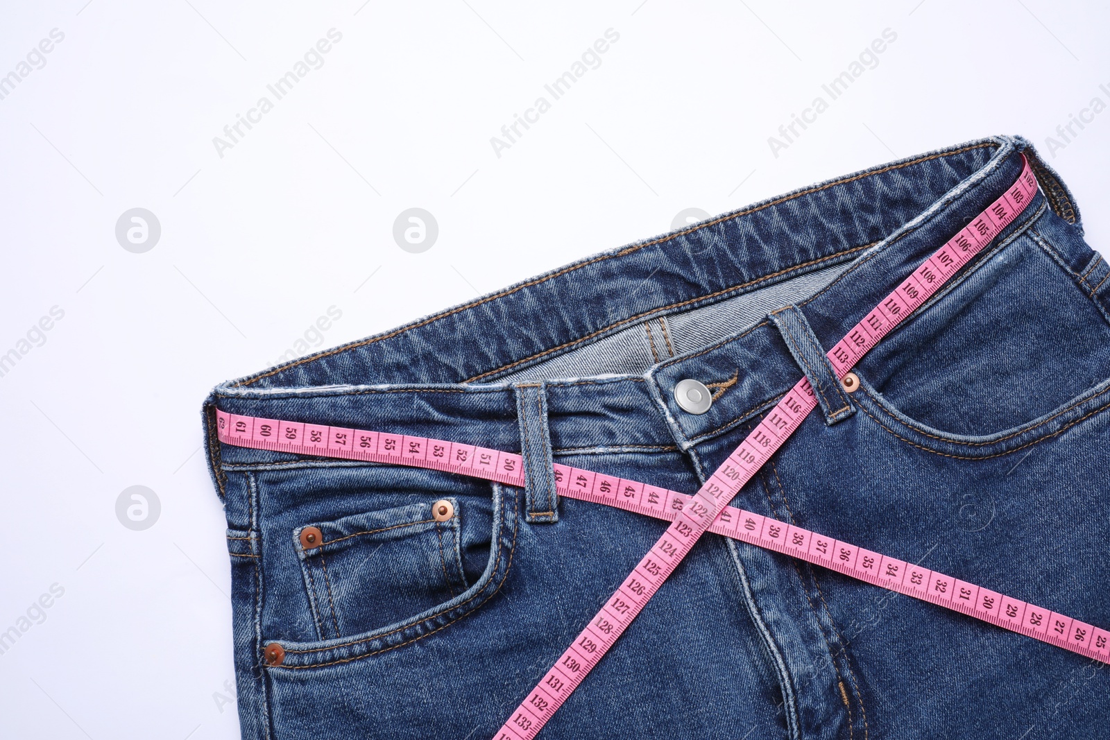 Photo of Jeans and measuring tape on white background, top view