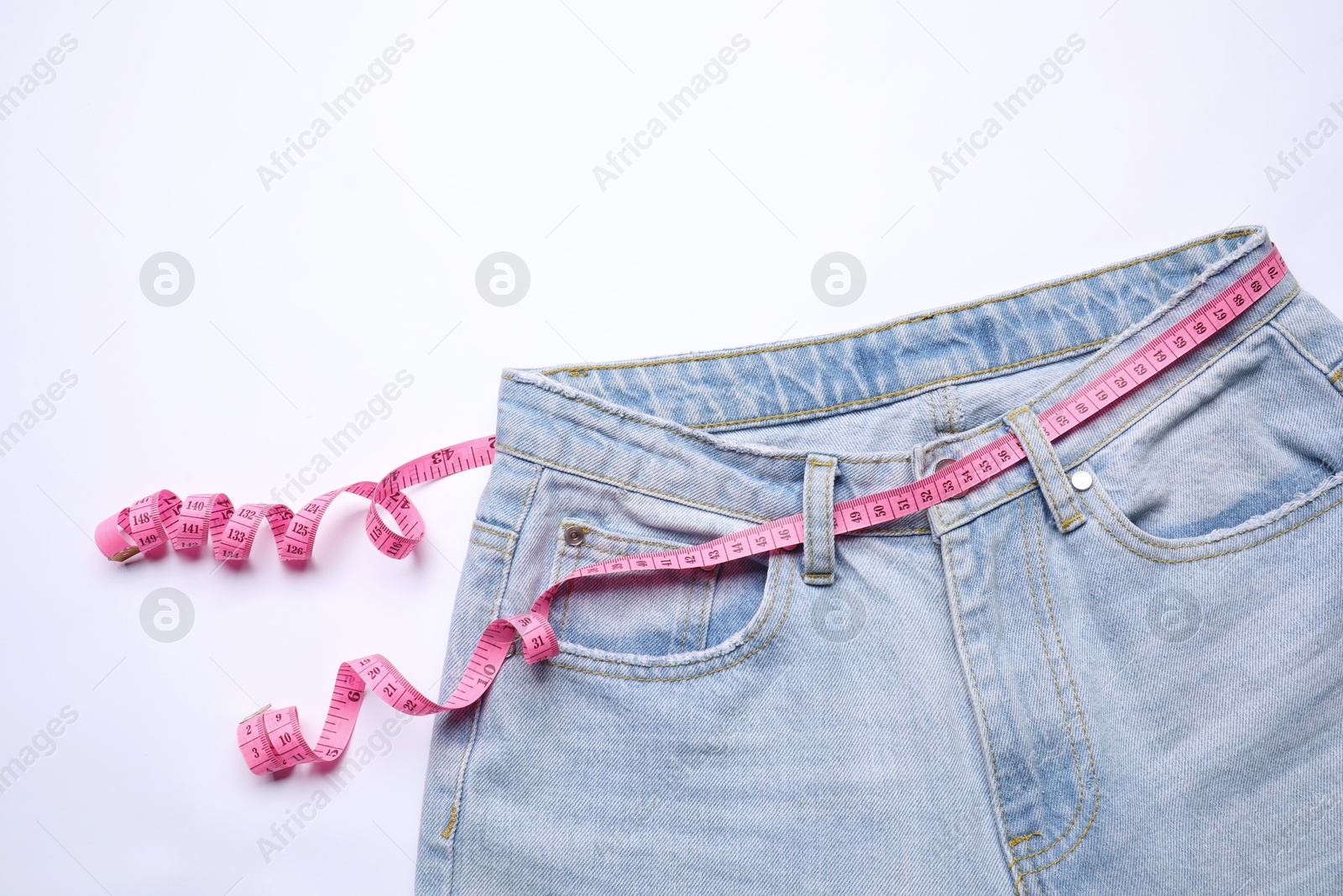 Photo of Jeans and measuring tape on white background, top view