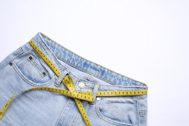 Photo of Jeans and measuring tape on white background, top view