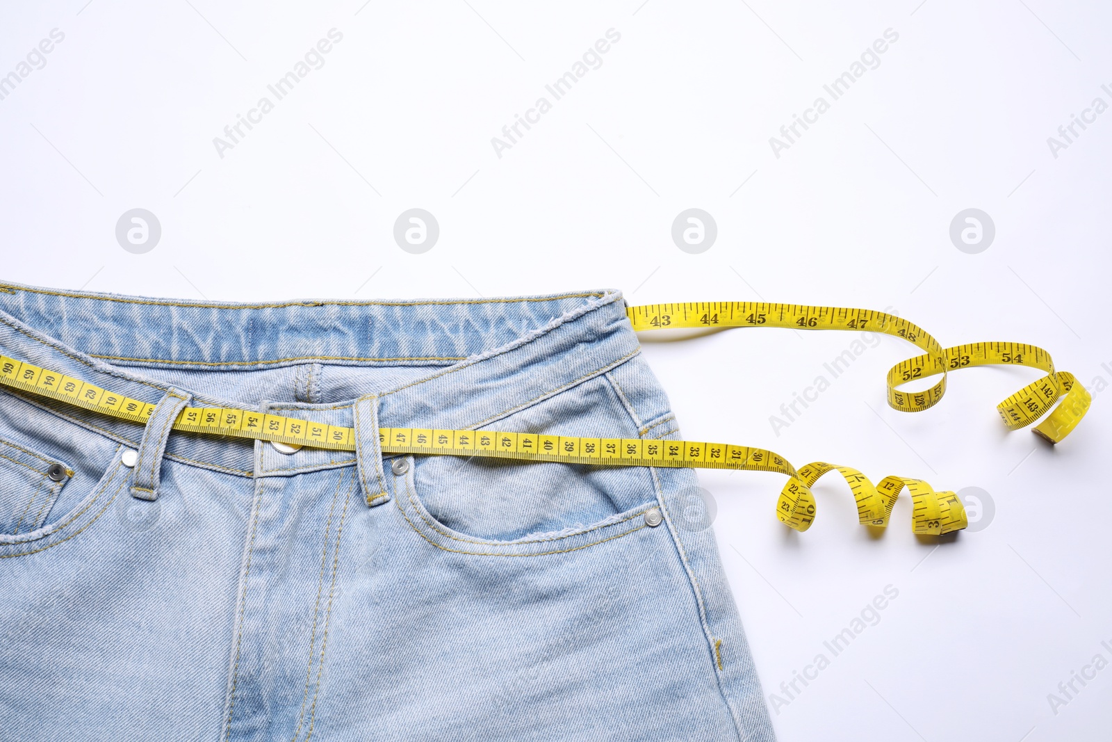 Photo of Jeans and measuring tape on white background, top view