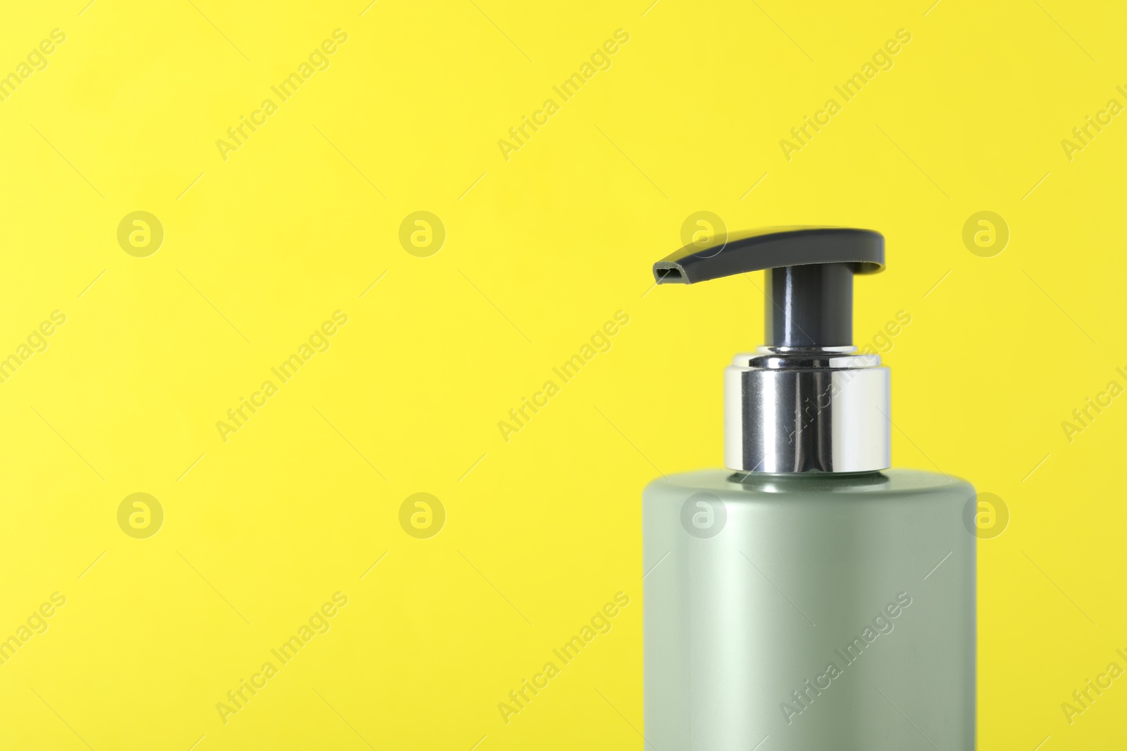 Photo of Shampoo in bottle on yellow background, closeup. Space for text