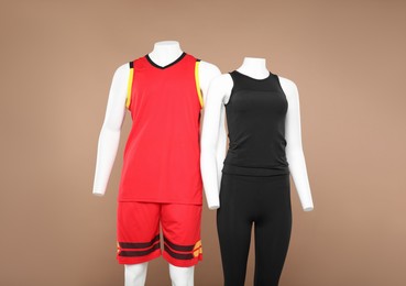 Photo of Female and male mannequins with stylish sports outfits on light brown background