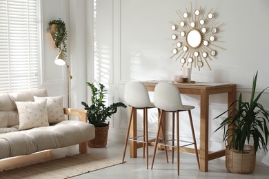 Photo of Bar stools near wooden table in room