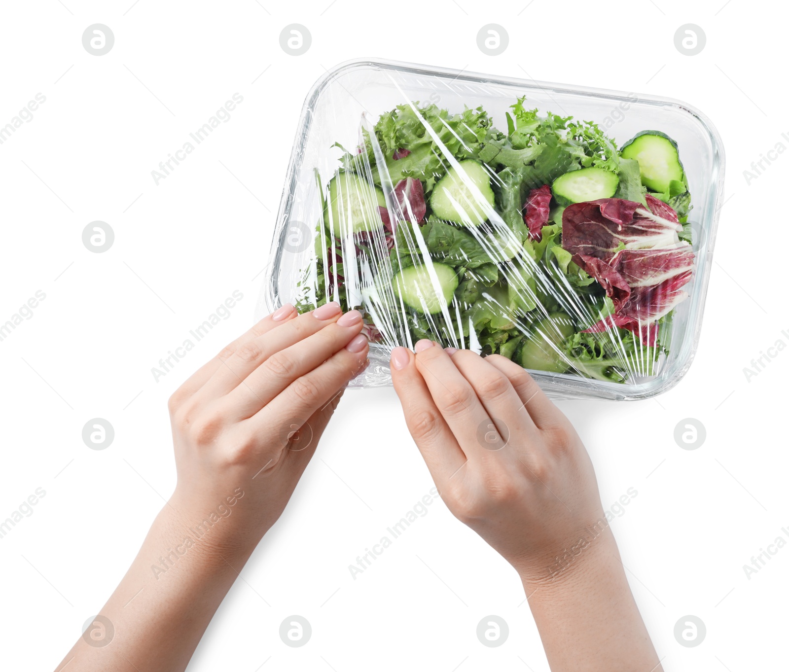 Photo of Woman putting plastic food wrap over glass container with fresh salad on white background, top view