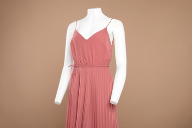 Female mannequin with stylish dress on light brown background