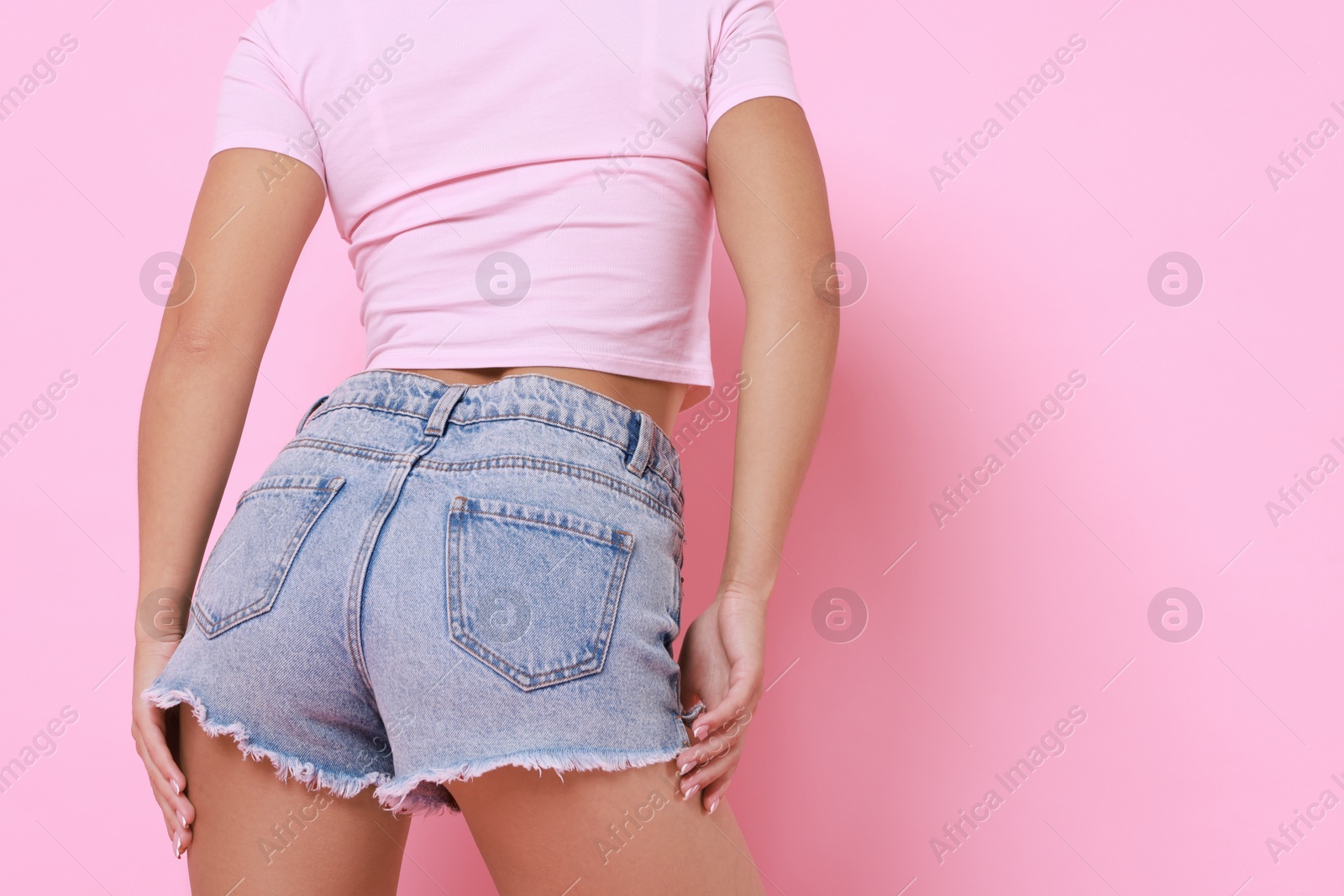 Photo of Woman wearing stylish denim shorts on pink background, closeup. Space for text