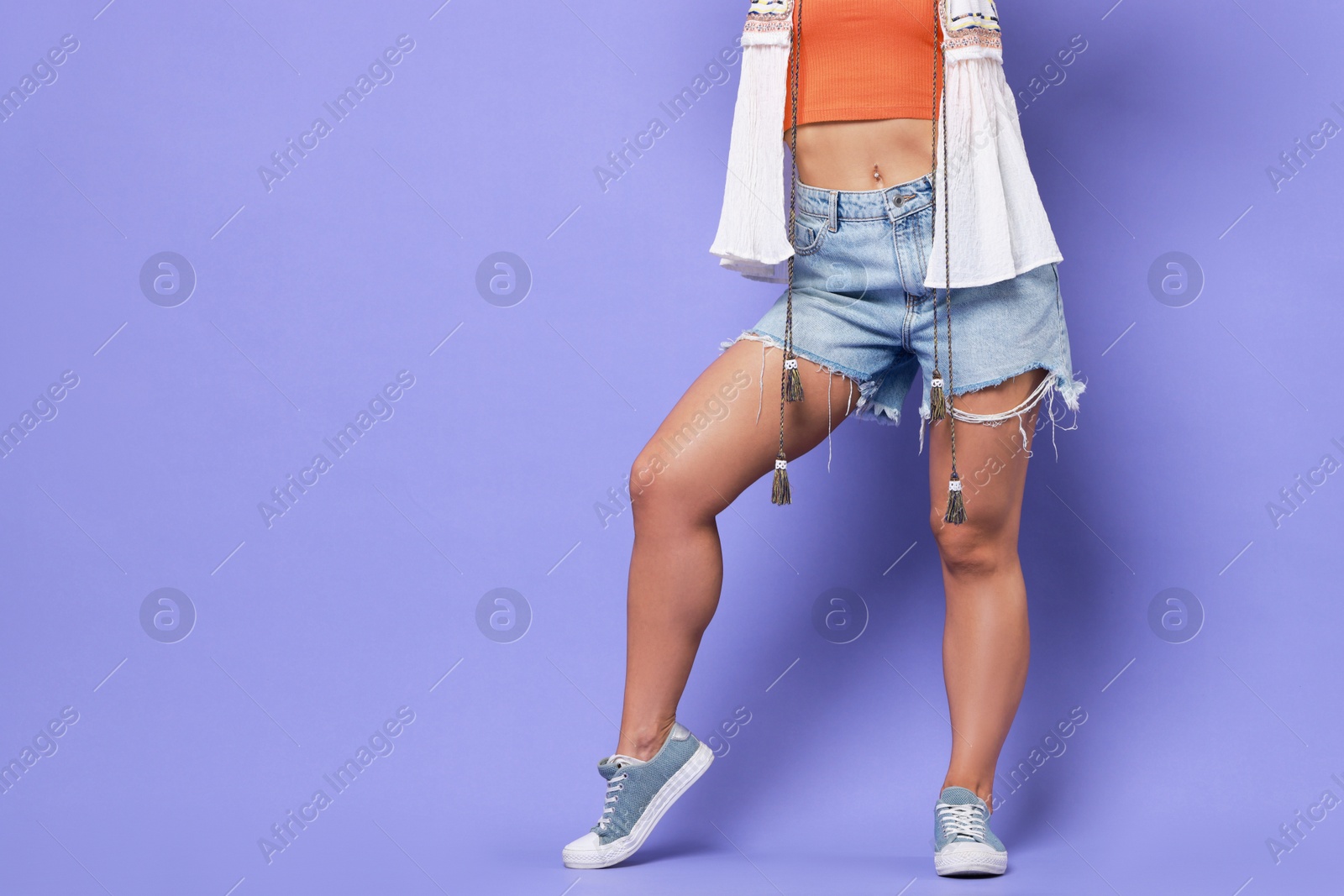 Photo of Woman wearing stylish denim shorts on violet background, closeup. Space for text