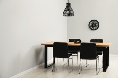 Photo of Wooden table with black chairs in stylish dining room