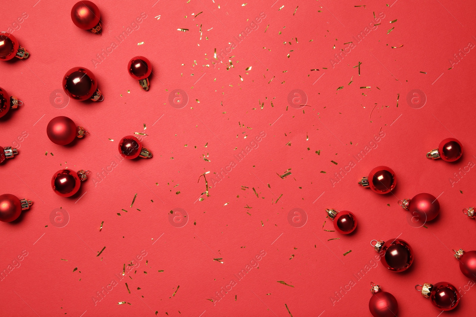 Photo of Christmas balls and confetti on red background, flat lay. Space for text