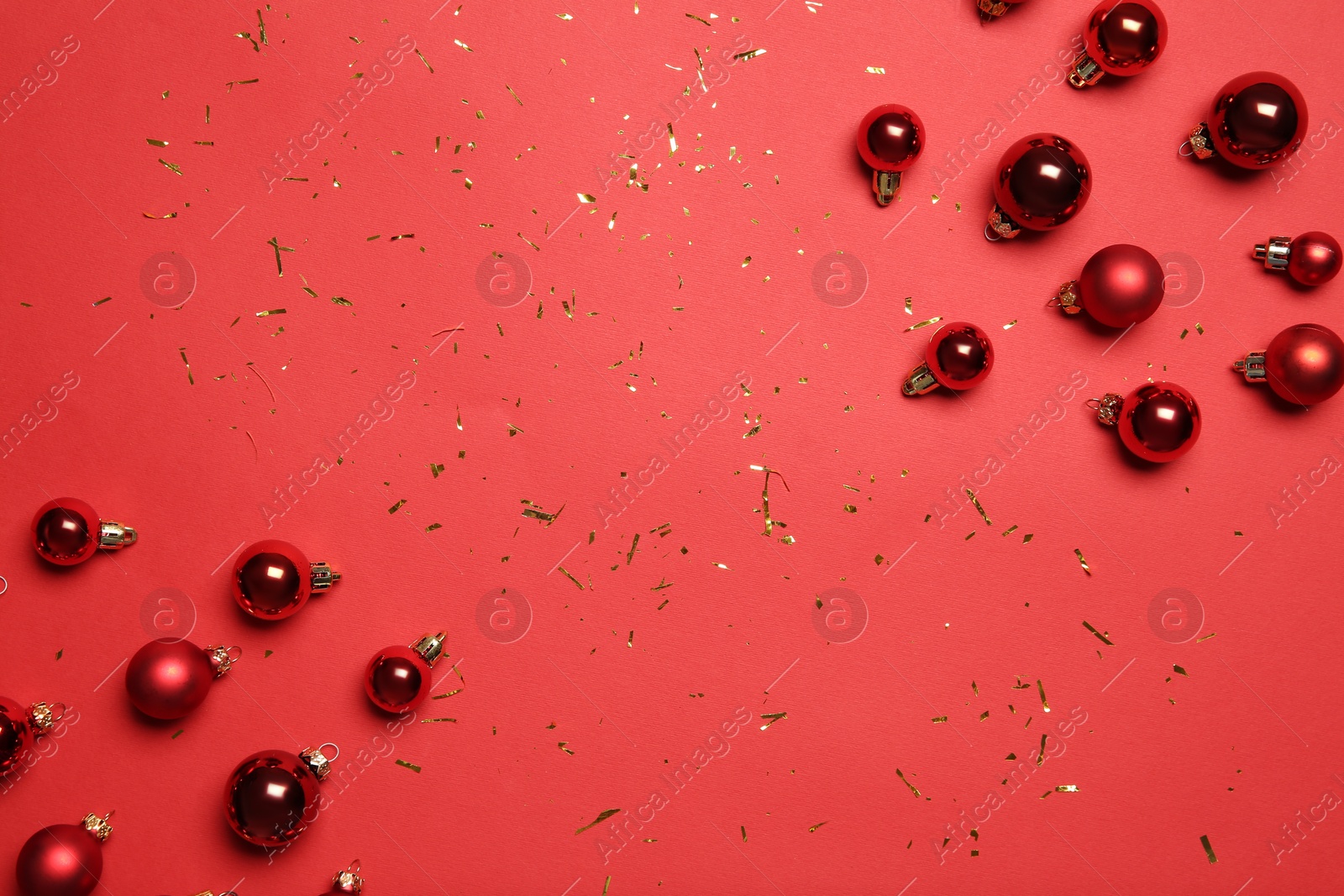 Photo of Christmas balls and confetti on red background, flat lay. Space for text