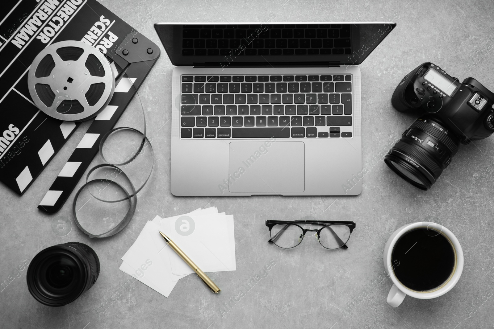 Photo of Flat lay composition with camera, film reel and laptop on grey textured table