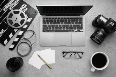 Flat lay composition with camera, film reel and laptop on grey textured table