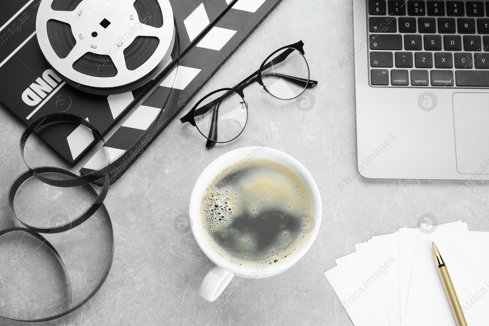 Photo of Flat lay composition with movie clapper, film reel and laptop on grey textured table