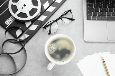 Flat lay composition with movie clapper, film reel and laptop on grey textured table