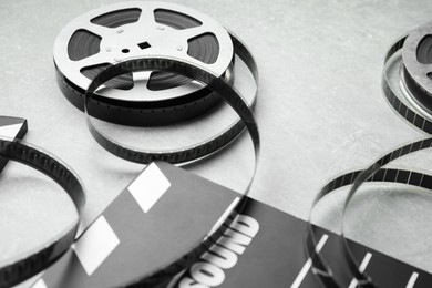 Photo of Movie clapper and film reels on grey textured table, closeup