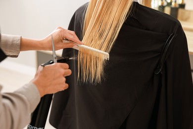 Photo of Hairdresser using spray while making stylish haircut in salon, closeup