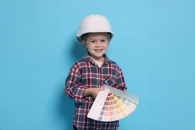 Photo of Little girl color palette pretending to be architect on light blue background. Dreaming of future profession