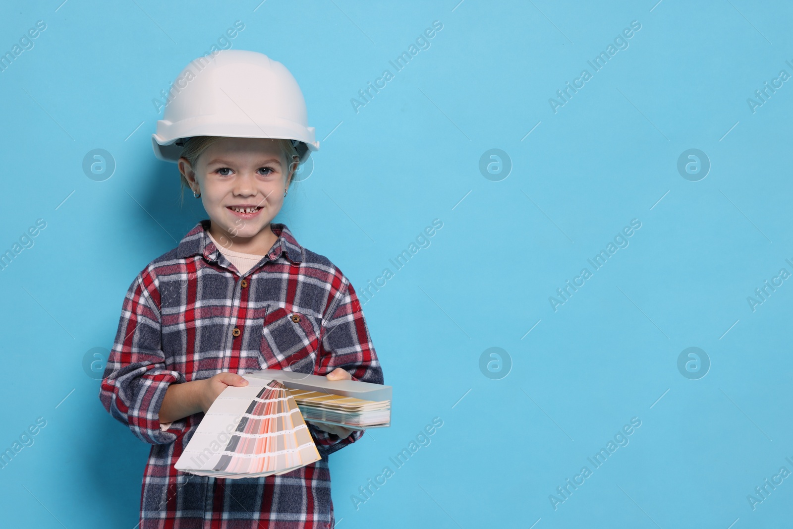 Photo of Little girl color palette pretending to be architect on light blue background, space for text. Dreaming of future profession