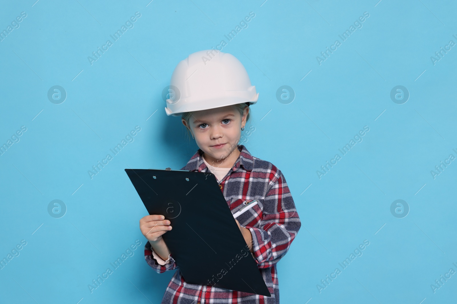 Photo of Little girl with clipboard pretending to be architect on light blue background. Dreaming of future profession