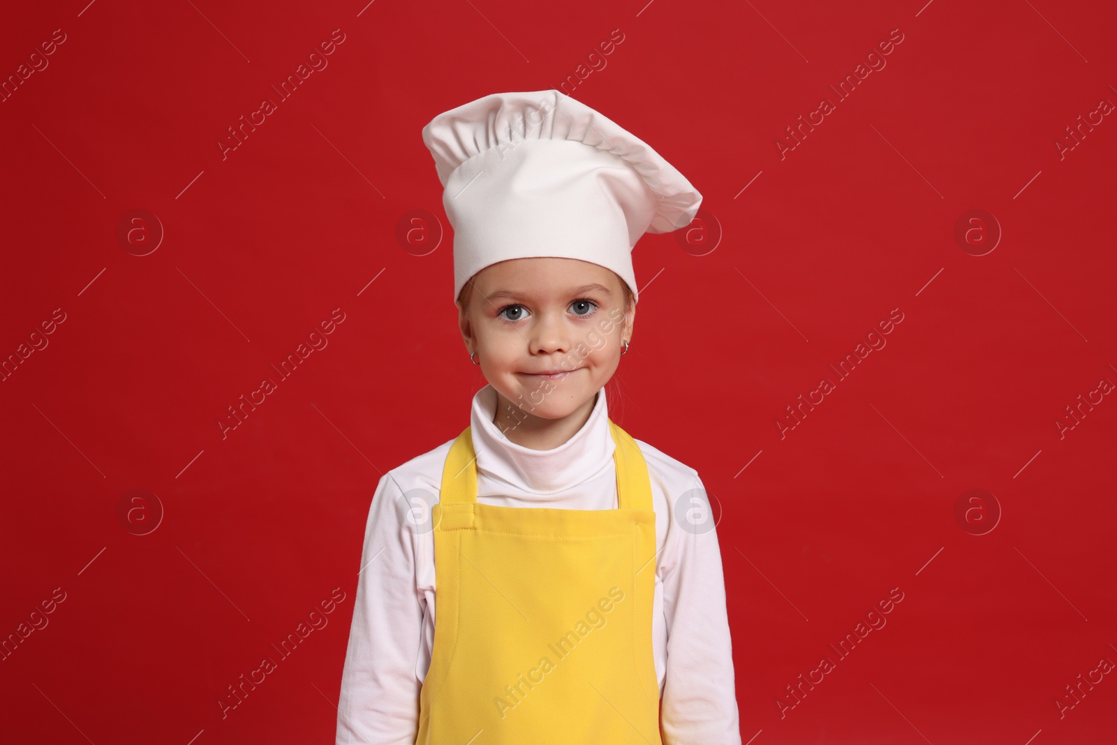 Photo of Little girl pretending to be chef on red background. Dreaming of future profession