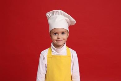 Photo of Little girl pretending to be chef on red background. Dreaming of future profession