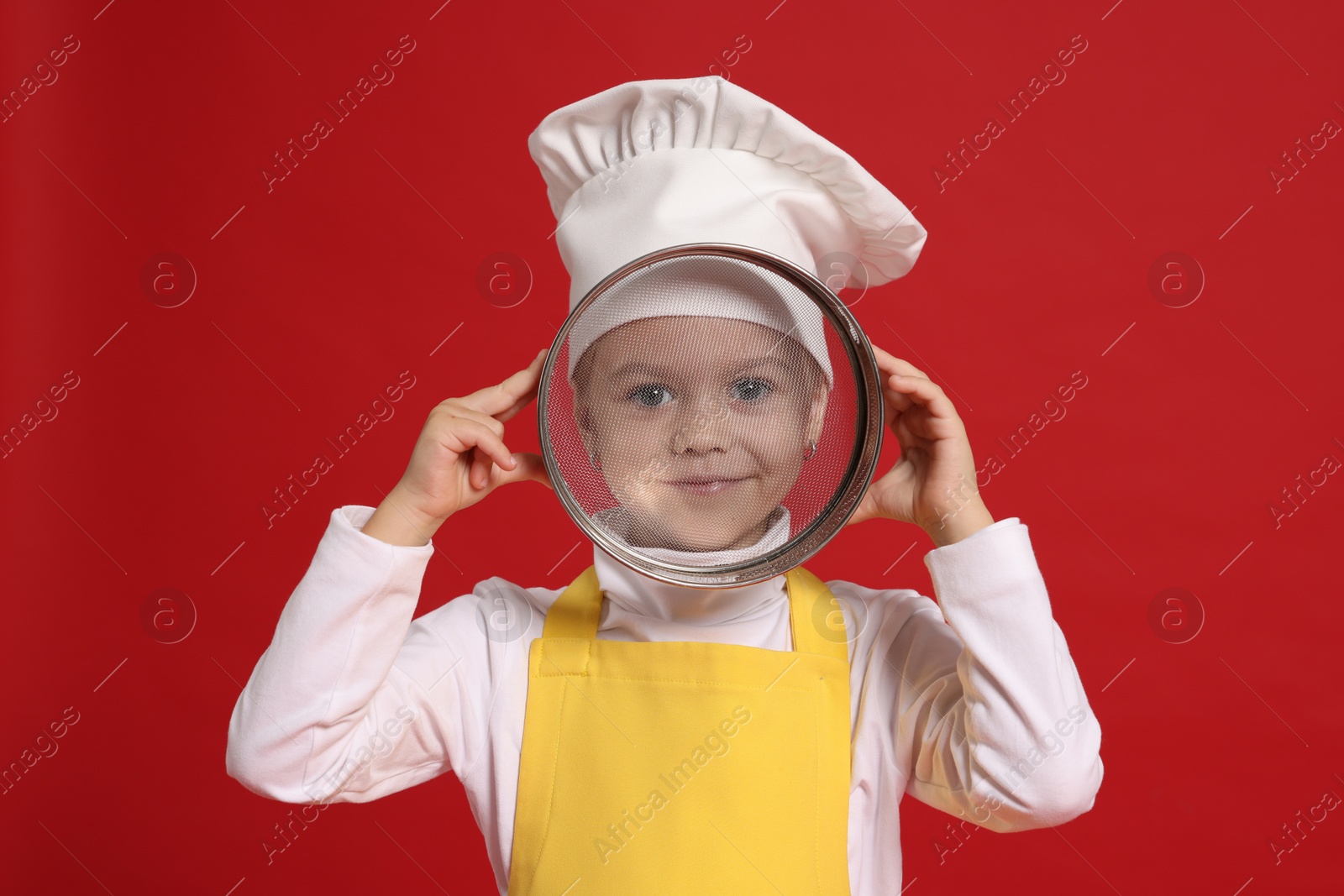 Photo of Little girl with sieve pretending to be chef on red background. Dreaming of future profession