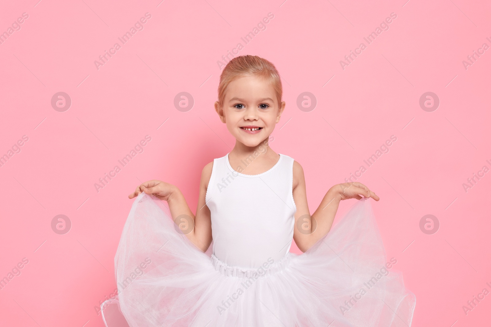 Photo of Little girl pretending to be ballerina on pink background. Dreaming of future profession