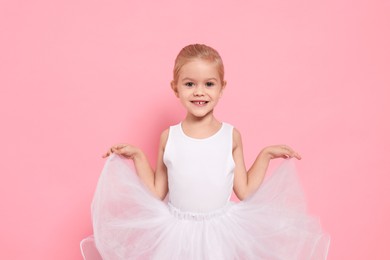 Little girl pretending to be ballerina on pink background. Dreaming of future profession