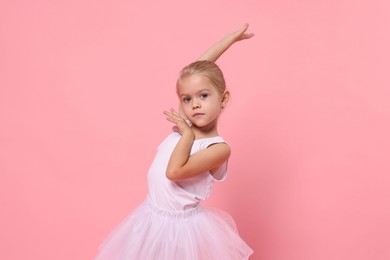 Little girl pretending to be ballerina on pink background. Dreaming of future profession