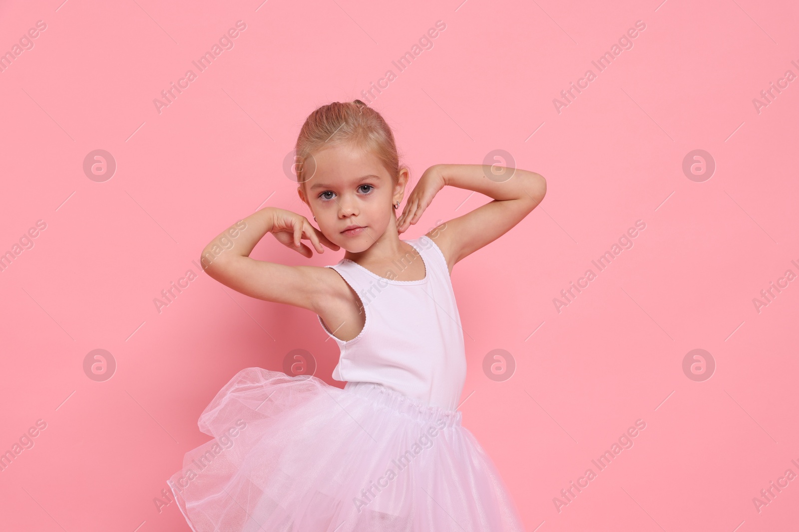 Photo of Little girl pretending to be ballerina on pink background. Dreaming of future profession