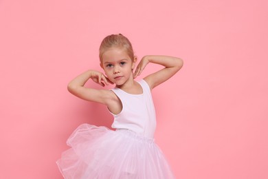 Photo of Little girl pretending to be ballerina on pink background. Dreaming of future profession